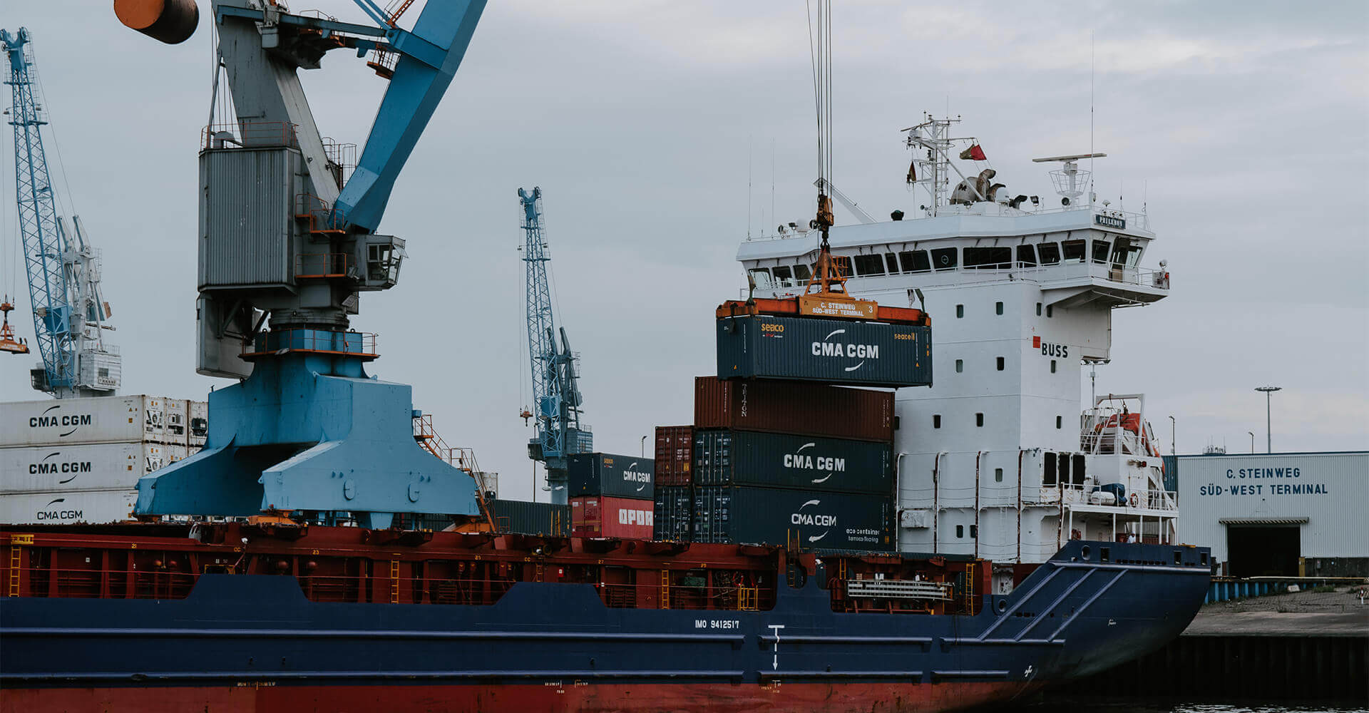 Cargo ship docked at C. Steinweg Süd-West Terminal with cranes unloading CMA CGM shipping containers.